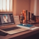 A desktop with office materials, books, and a laptop showing photos of a child in dim lighting