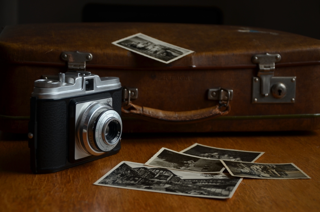 An old school camera with black and white photos on a wooden table