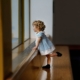 Little girl in a blue dress looking out the window