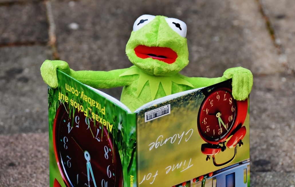 Kermit the frog holding a picture book with writing upside down