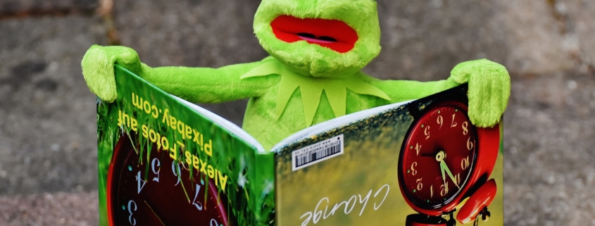 Kermit the frog holding a picture book with writing upside down