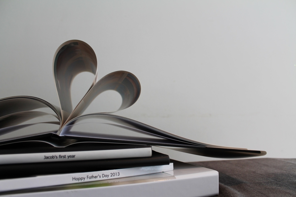 A small pile of photo books in black and while with the top one's pages forming a heart