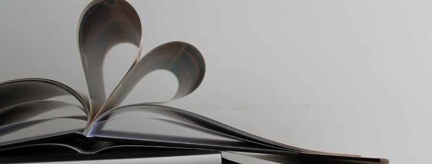 A small pile of photo books in black and while with the top one's pages forming a heart