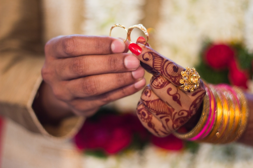 Closeup of two hands holding wedding rings at an Indian wedding