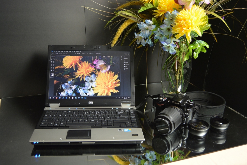 Photo editing software on a table with a DSLR camera and flowers