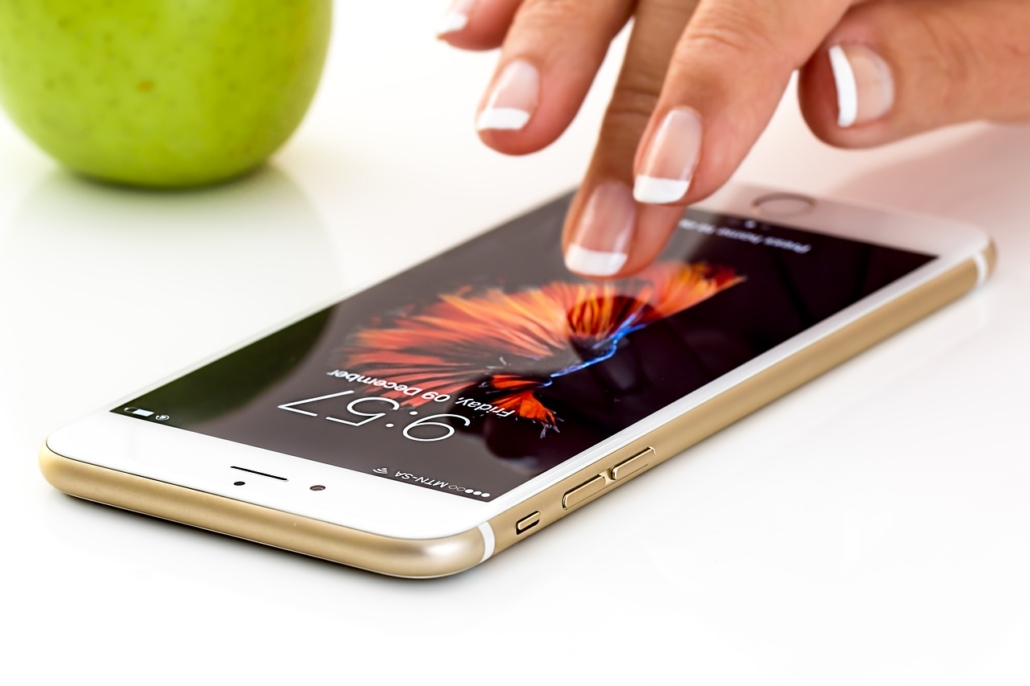 Woman tapping her iPhone on a white table with an apple in the background