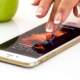 Woman tapping her iPhone on a white table with an apple in the background