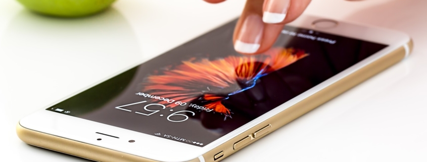 Woman tapping her iPhone on a white table with an apple in the background