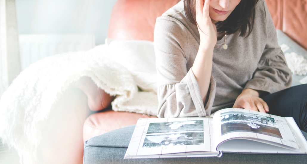 Woman on a couch browsing through a photo book